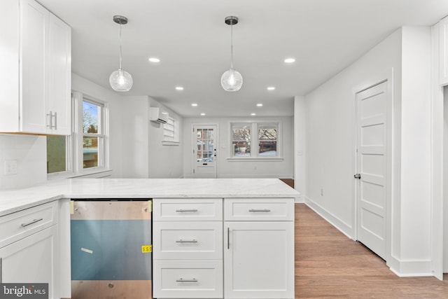 kitchen featuring a wall mounted air conditioner, white cabinets, light stone counters, and decorative light fixtures