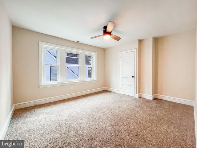 carpeted spare room featuring ceiling fan