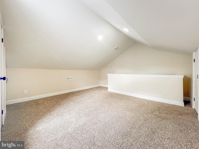 additional living space featuring vaulted ceiling and carpet flooring