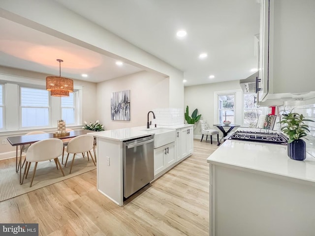 kitchen with sink, hanging light fixtures, white cabinets, stainless steel dishwasher, and kitchen peninsula