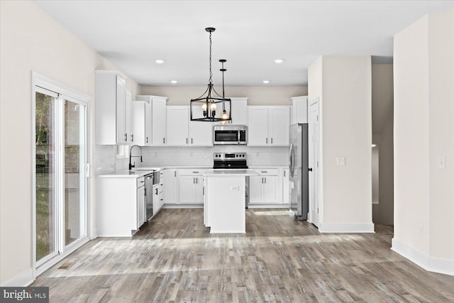 kitchen with white cabinetry, stainless steel appliances, decorative light fixtures, and a kitchen island