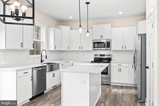 kitchen featuring pendant lighting, sink, white cabinets, a center island, and stainless steel appliances