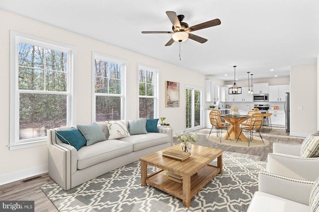 living room featuring ceiling fan, sink, and light hardwood / wood-style flooring