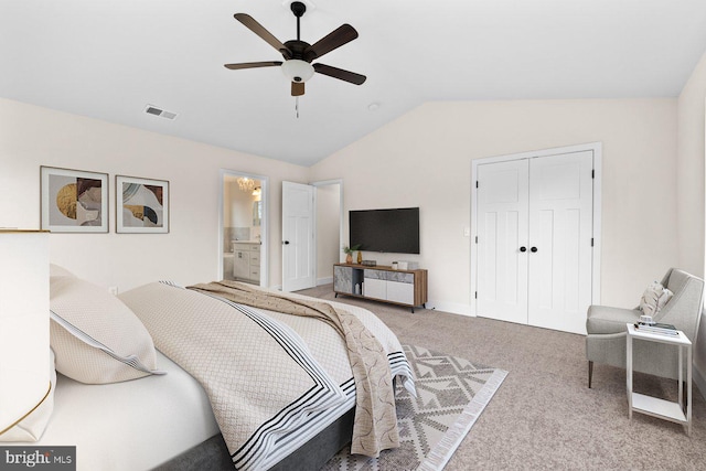 carpeted bedroom featuring lofted ceiling, ensuite bath, ceiling fan, and a closet