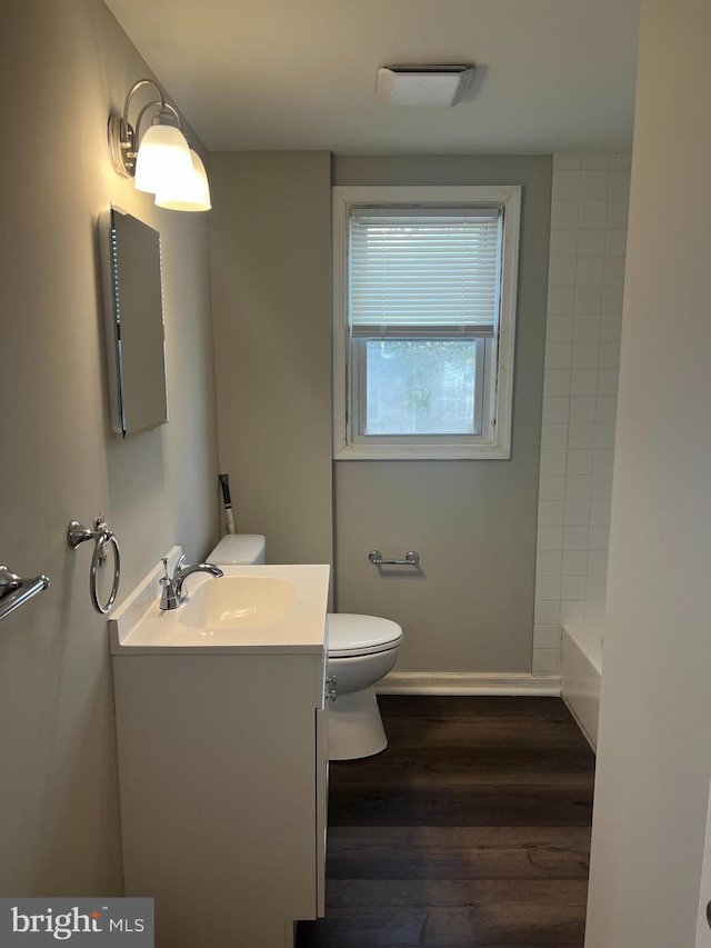 bathroom with vanity, hardwood / wood-style floors, a tub, and toilet