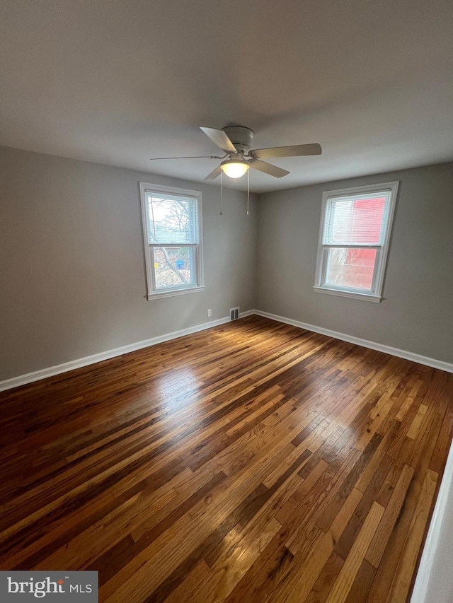 unfurnished room featuring ceiling fan, plenty of natural light, and dark hardwood / wood-style flooring