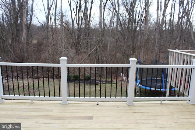 wooden deck featuring a trampoline and a lawn