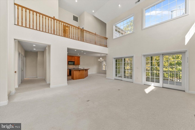 unfurnished living room featuring baseboards, visible vents, light colored carpet, a notable chandelier, and recessed lighting