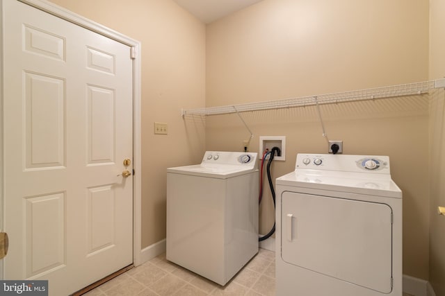 laundry area with washing machine and dryer and light tile patterned floors