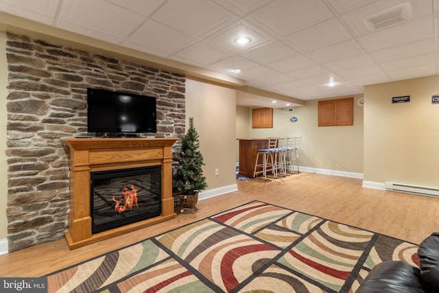 living room featuring a baseboard radiator, indoor bar, and light wood-type flooring