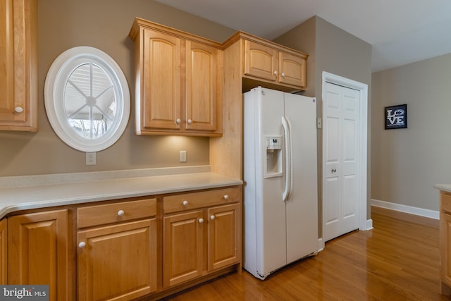 kitchen featuring light hardwood / wood-style floors, white fridge with ice dispenser, and light brown cabinets