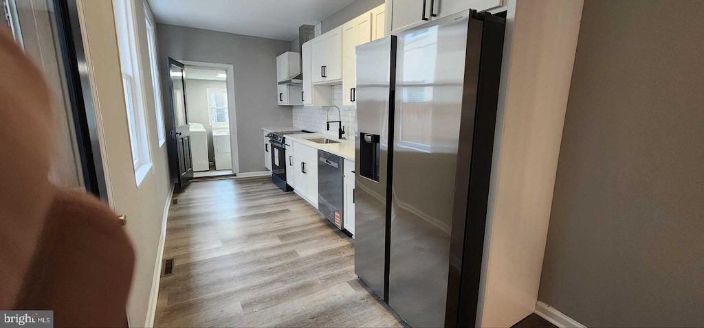 kitchen featuring sink, white cabinets, backsplash, black appliances, and light hardwood / wood-style flooring