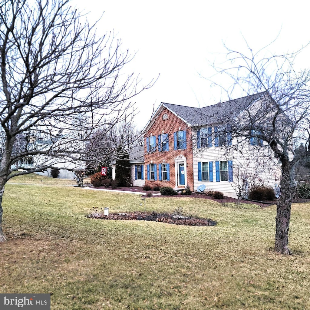 colonial home featuring brick siding and a front yard