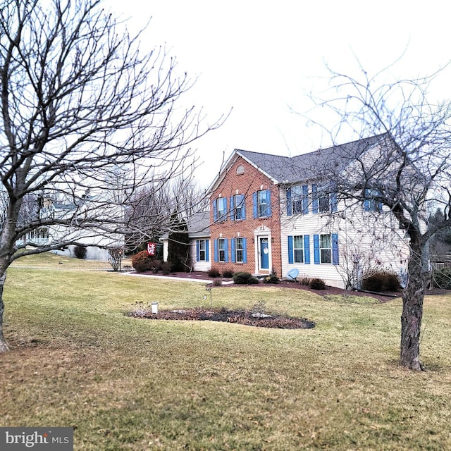 colonial home featuring brick siding and a front yard