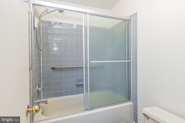 bathroom with toilet and combined bath / shower with glass door