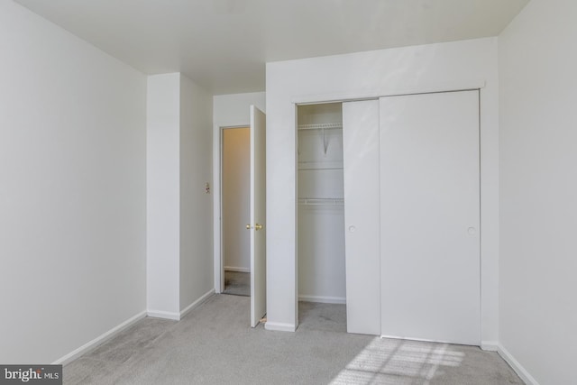 unfurnished bedroom with light carpet and a closet