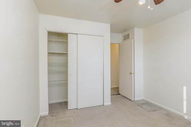 unfurnished bedroom featuring light carpet, ceiling fan, and a closet