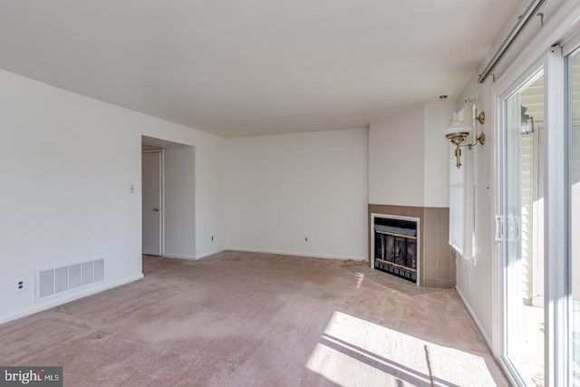 unfurnished living room featuring light carpet and a tile fireplace