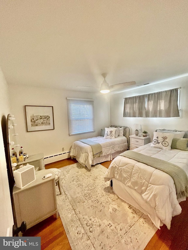 bedroom with hardwood / wood-style flooring, ceiling fan, and baseboard heating