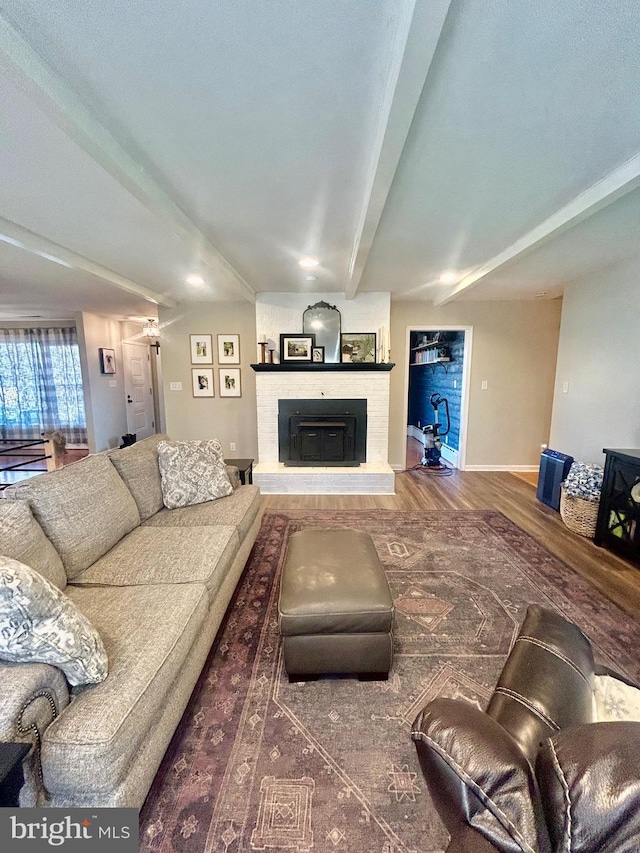 living room with beamed ceiling, dark hardwood / wood-style flooring, and a brick fireplace