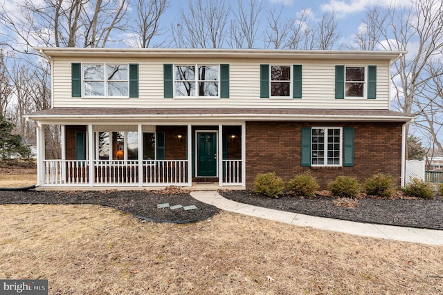 front facade featuring covered porch and a front yard