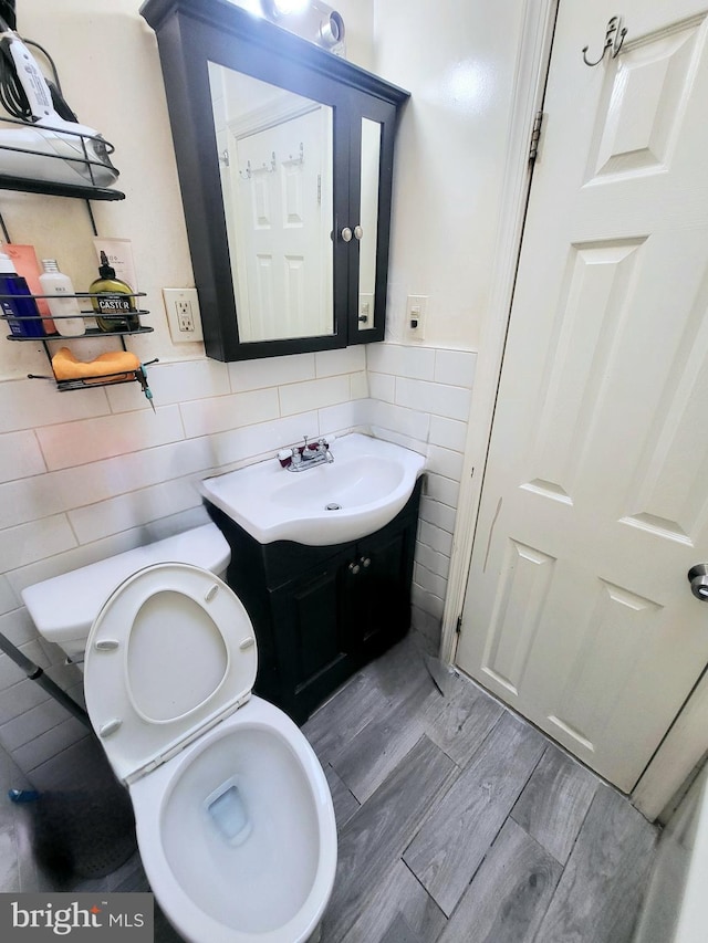 bathroom featuring hardwood / wood-style flooring, vanity, toilet, and tile walls