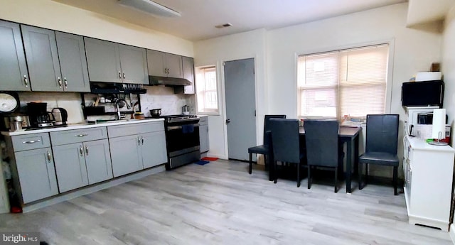 kitchen with backsplash, sink, light hardwood / wood-style floors, and range with electric stovetop