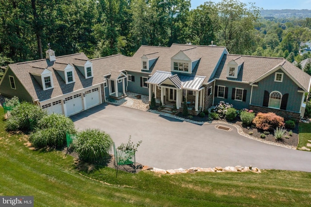 view of front of house with driveway, metal roof, an attached garage, a standing seam roof, and a front yard