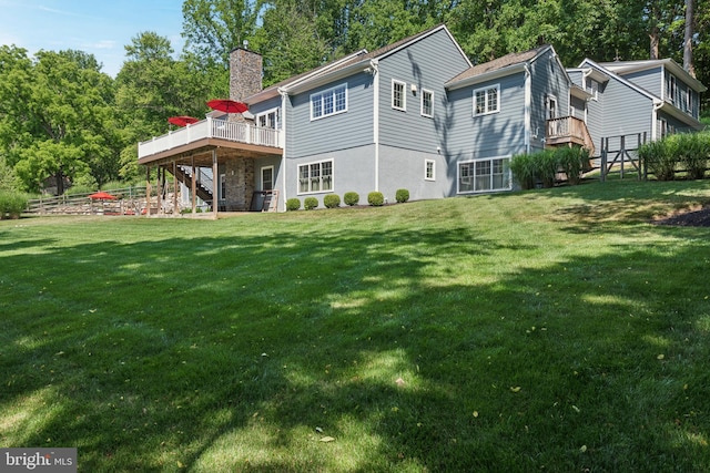 rear view of house with a deck, a lawn, a chimney, and stairs