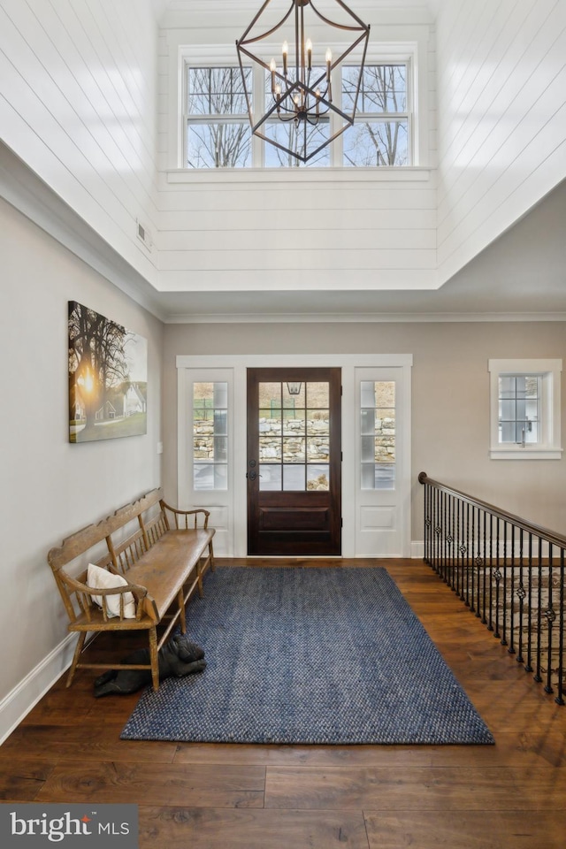 foyer entrance featuring a healthy amount of sunlight, a towering ceiling, and wood finished floors