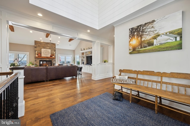 living area featuring a large fireplace, lofted ceiling with beams, wood finished floors, and a healthy amount of sunlight