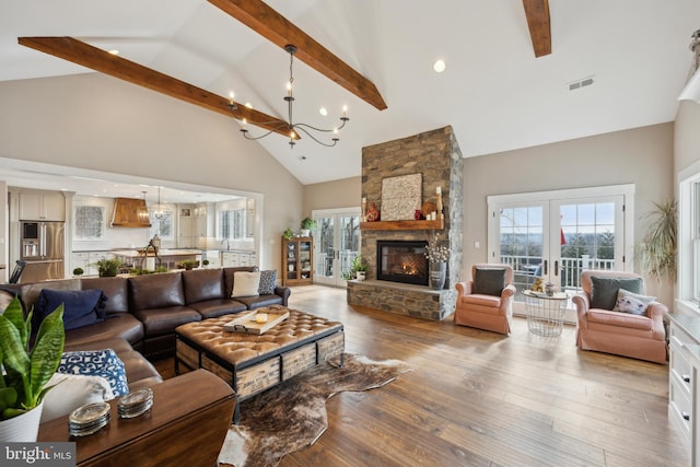 living room featuring a fireplace, high vaulted ceiling, visible vents, a chandelier, and hardwood / wood-style flooring