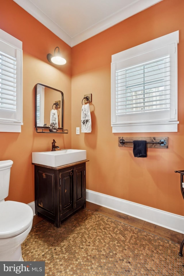 bathroom with ornamental molding, baseboards, vanity, and toilet