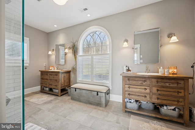 full bathroom featuring baseboards, visible vents, two vanities, and a sink