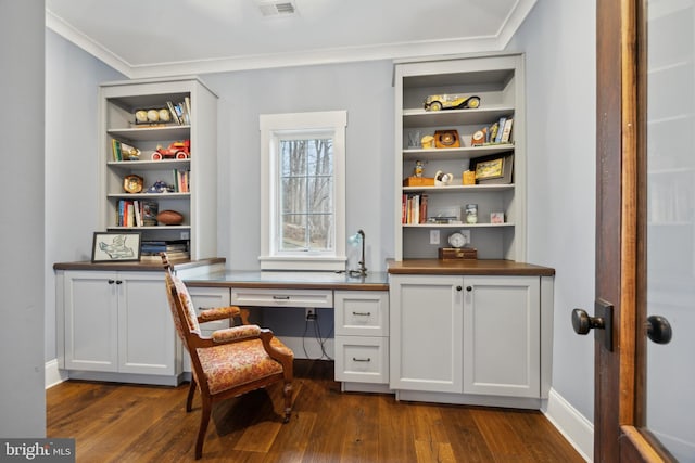 office with visible vents, baseboards, built in study area, dark wood-style floors, and ornamental molding