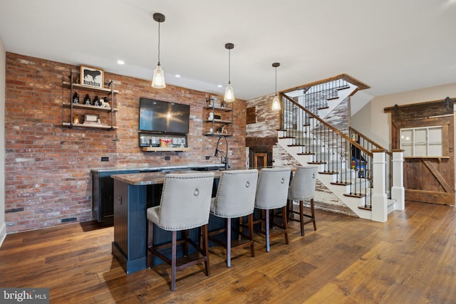 bar featuring stairs, indoor wet bar, dark wood finished floors, and a barn door