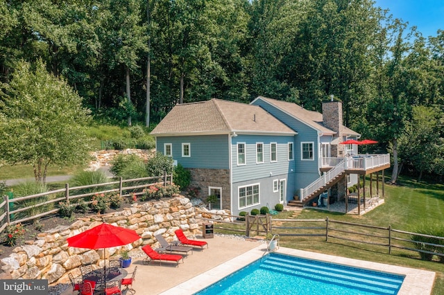 rear view of property with a deck, a yard, stone siding, stairway, and a chimney