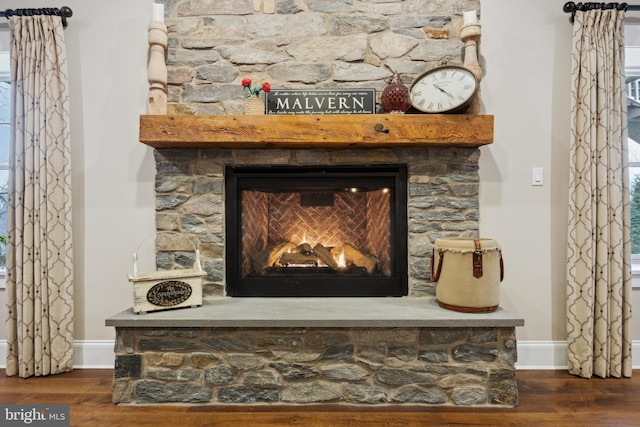 details featuring a stone fireplace, wood finished floors, and baseboards