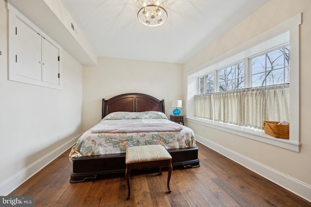 bedroom featuring an inviting chandelier, hardwood / wood-style flooring, and baseboards