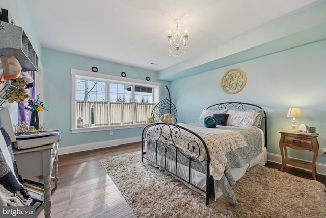 bedroom with an inviting chandelier, wood finished floors, and baseboards