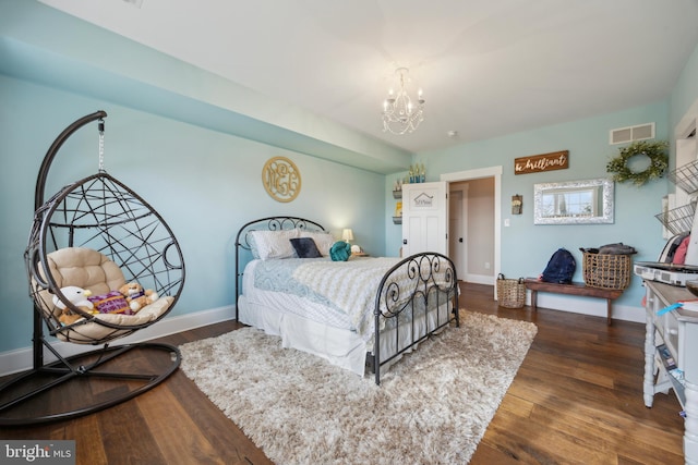 bedroom featuring a chandelier, wood finished floors, visible vents, and baseboards