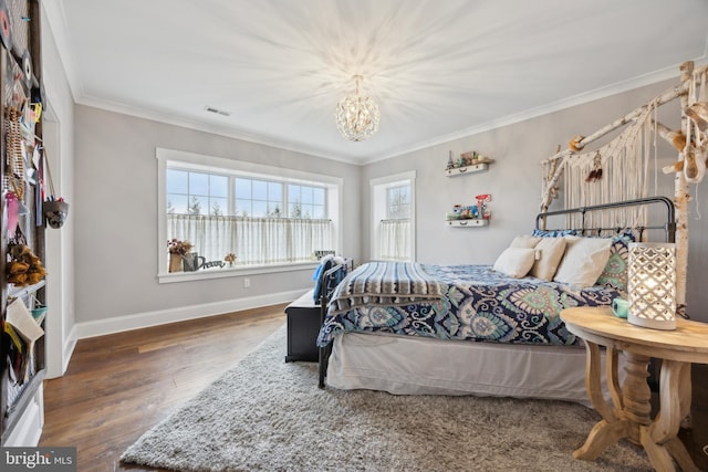 bedroom with a notable chandelier, crown molding, visible vents, wood finished floors, and baseboards