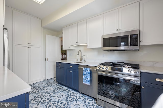 kitchen featuring stainless steel appliances, white cabinetry, sink, and blue cabinets