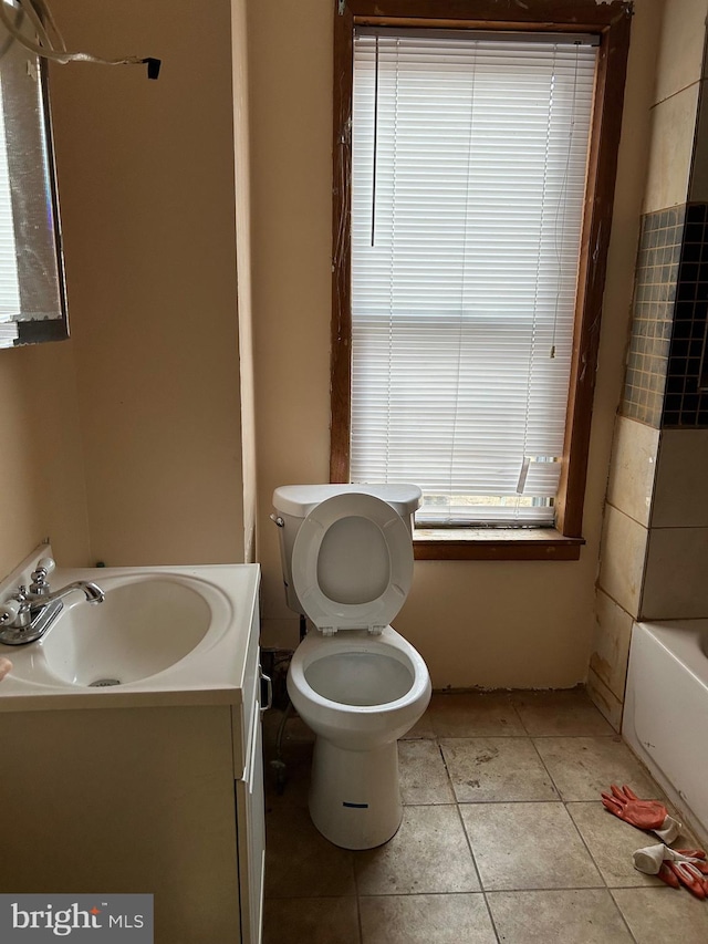 bathroom featuring vanity, a bathtub, tile patterned floors, and toilet