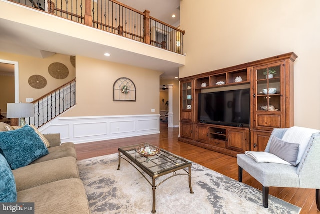 living room with a wainscoted wall, stairs, recessed lighting, wood finished floors, and a decorative wall