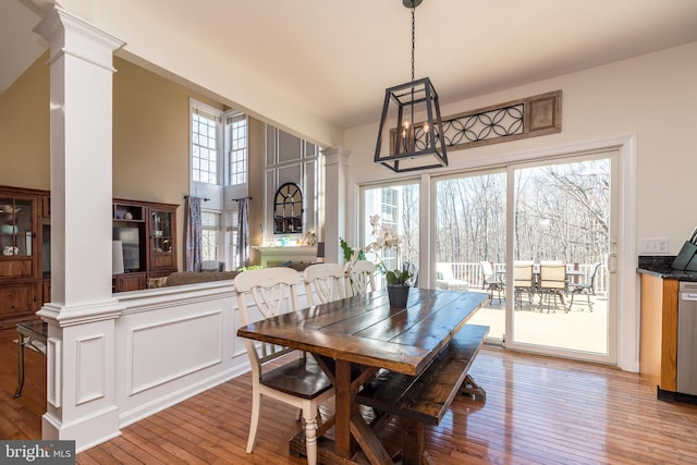 dining area with a healthy amount of sunlight, hardwood / wood-style floors, and decorative columns