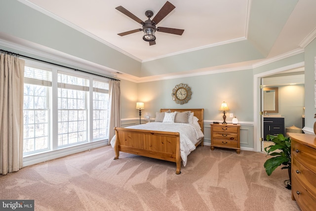 carpeted bedroom featuring crown molding, a decorative wall, a ceiling fan, and a wainscoted wall