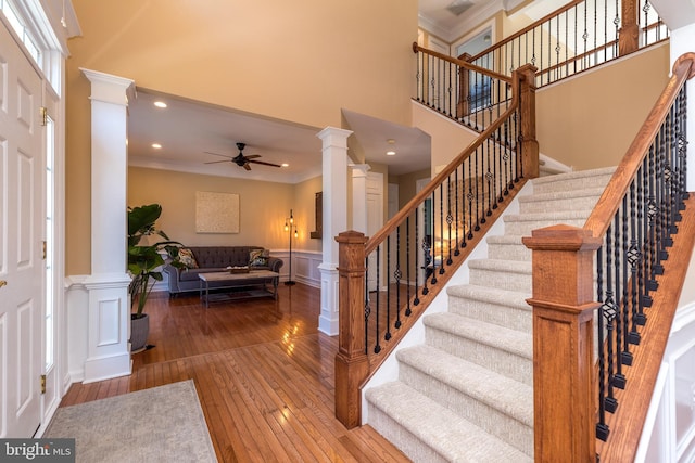 entrance foyer featuring a ceiling fan, crown molding, ornate columns, and wood-type flooring