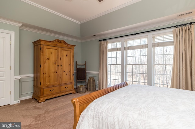 carpeted bedroom featuring a decorative wall, a wainscoted wall, crown molding, and visible vents