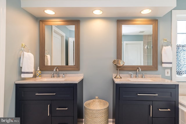 full bathroom with two vanities, recessed lighting, and a sink